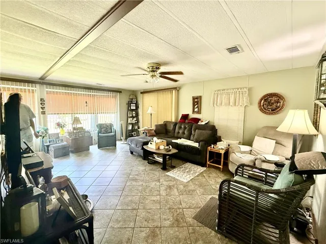 Spacious living area featuring tile flooring, a textured ceiling with decorative beams, and a ceiling fan