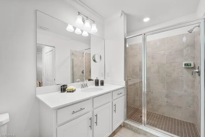 Bathroom featuring a stall shower, vanity, and ornamental molding