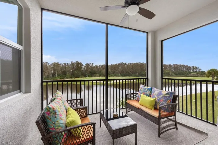 Sunroom / solarium with view of wooded area, a balcony, ceiling fan, and an outdoor hangout area