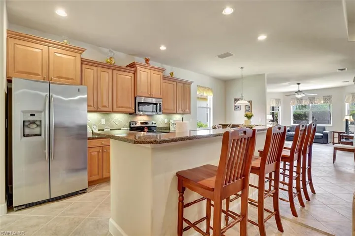 Kitchen with a breakfast bar, light tile patterned floors, stainless steel appliances, decorative backsplash, and pendant lighting