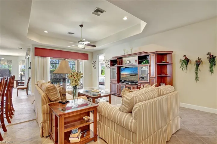 Tiled living room with ceiling fan and a tray ceiling