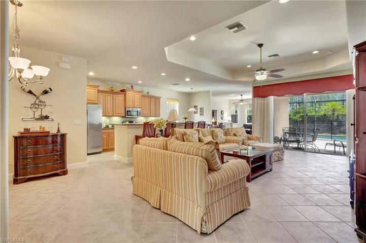 Living room with light tile patterned flooring, a tray ceiling, and ceiling fan