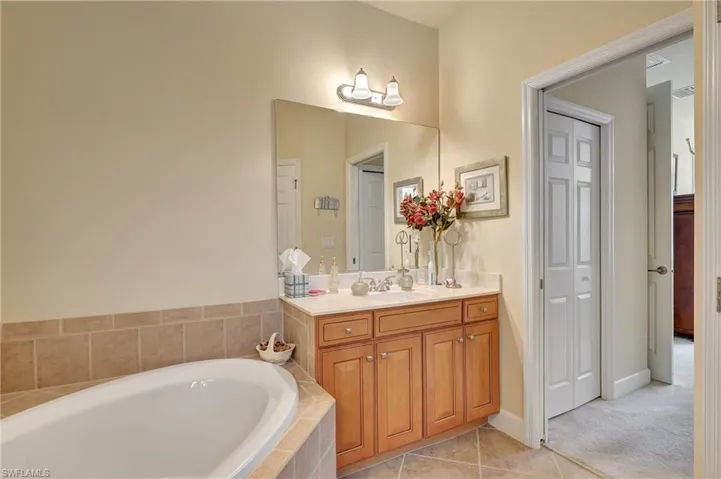 Bathroom with vanity, tiled bath, and tile patterned floors