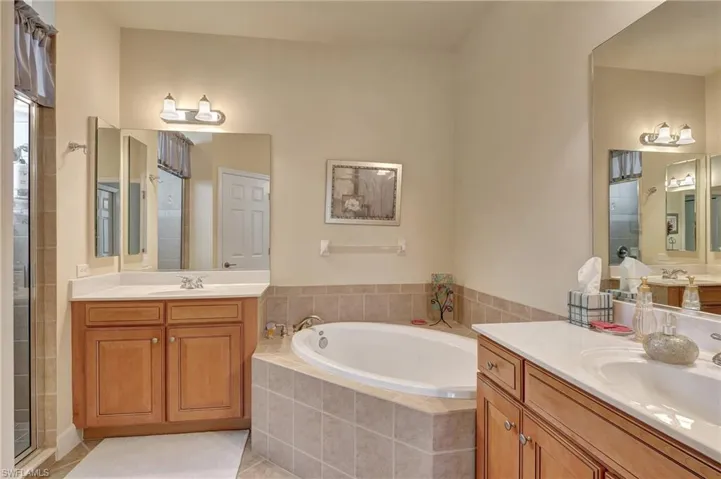 Bathroom with independent shower and bath, tile patterned flooring, and dual bowl vanity
