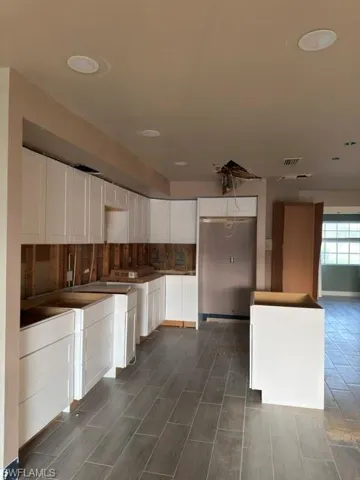 Kitchen featuring new white shaker-style cabinetry, a stainless steel refrigerator, recessed ceiling lighting, and wood-finish tile flooring