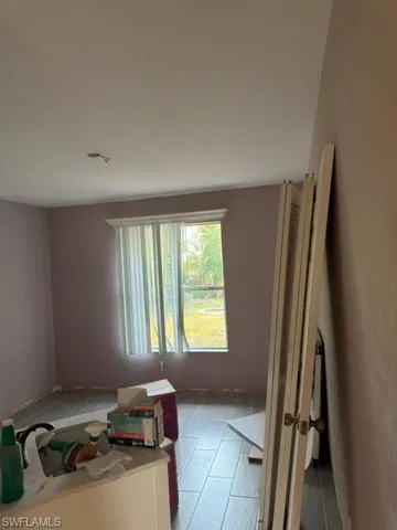 Room featuring wood-look tile flooring, a window with horizontal blinds, and a decorative window cornice
