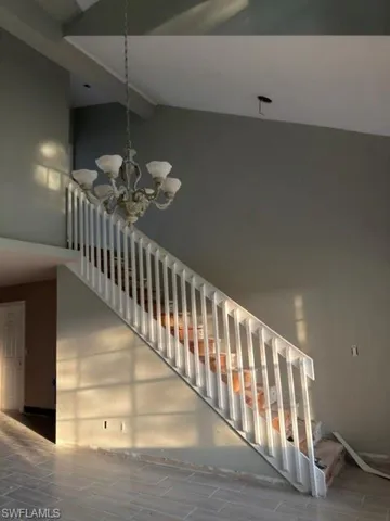 Two-story entry featuring vaulted ceilings, a decorative chandelier, and a prominent staircase with white railings