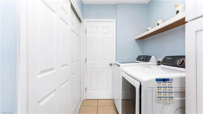Clothes washing area with independent washer and dryer and light tile patterned floors