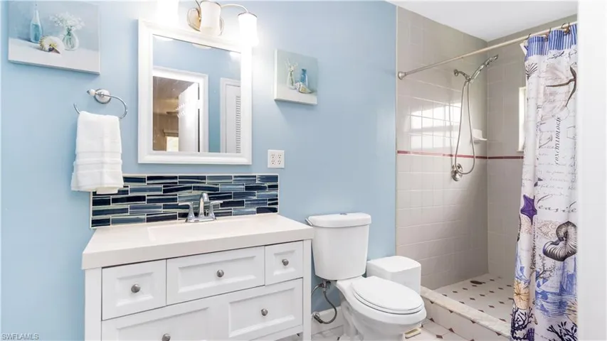 Bathroom featuring vanity, toilet, tasteful backsplash, and a shower with shower curtain