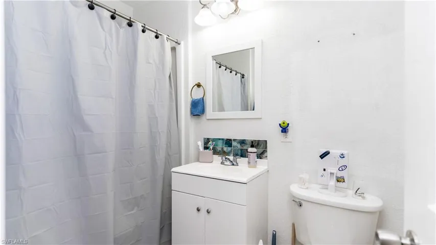 Bathroom featuring a shower with curtain, vanity, and toilet