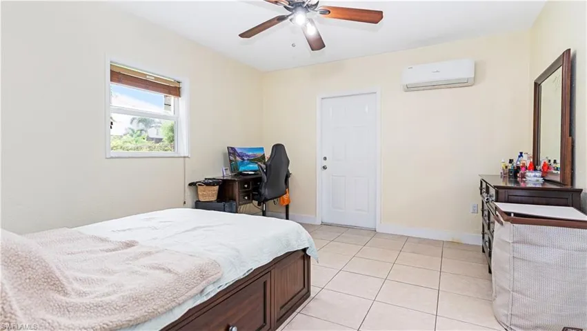 Bedroom with light tile patterned flooring, ceiling fan, and a wall mounted air conditioner