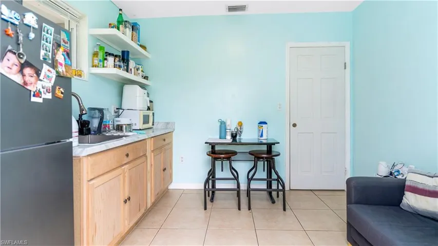 Bar featuring refrigerator, light brown cabinetry, sink, and light tile patterned floors