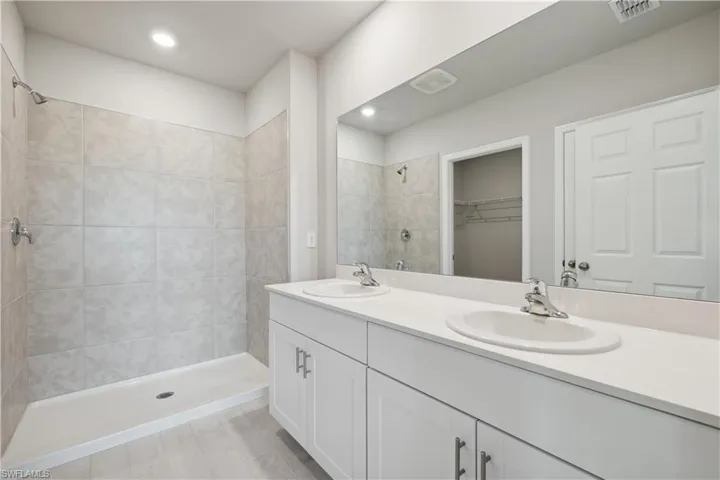 Bathroom with a tile shower, hardwood / wood-style floors, dual sinks, and large vanity