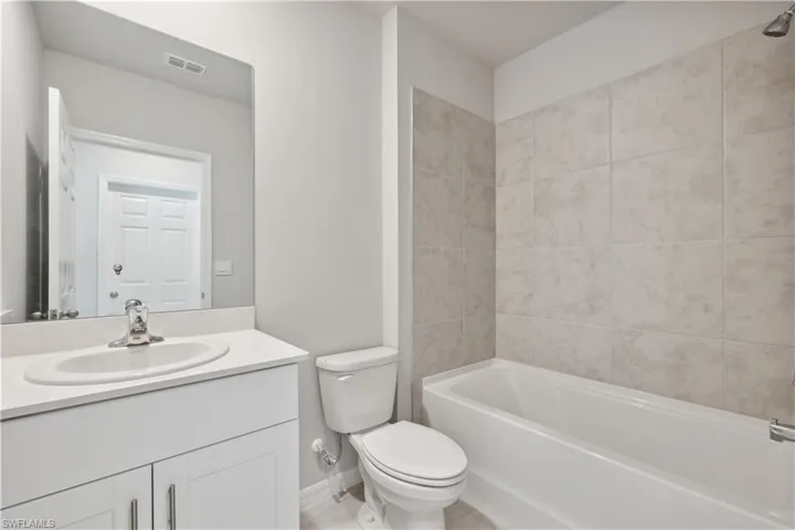 Full bathroom featuring tiled shower / bath, large vanity, and toilet
