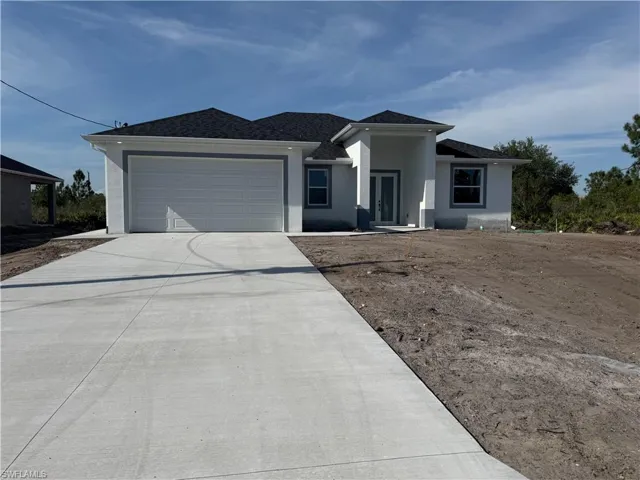 View of front facade featuring a garage, stucco siding, and concrete driveway