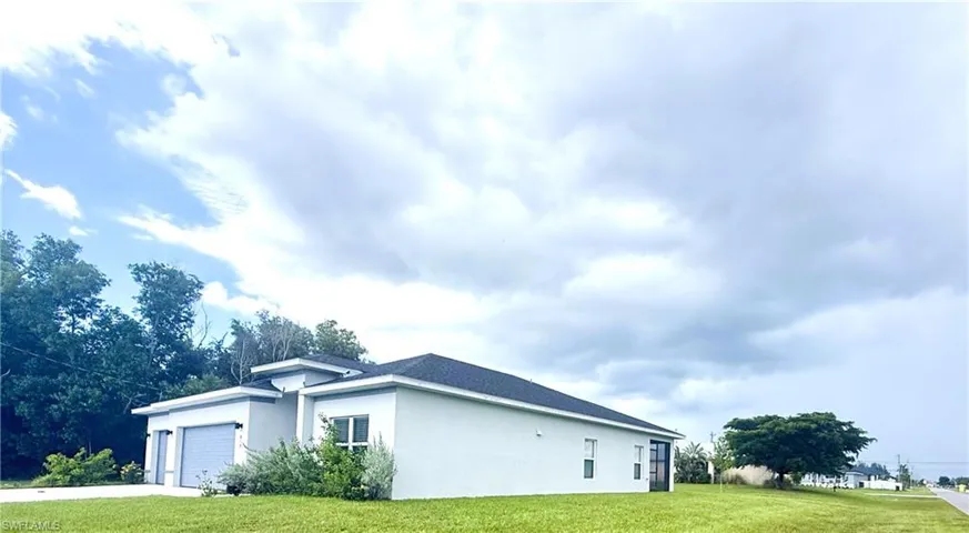 View of home's exterior featuring a lawn, stucco siding, an attached garage, and driveway