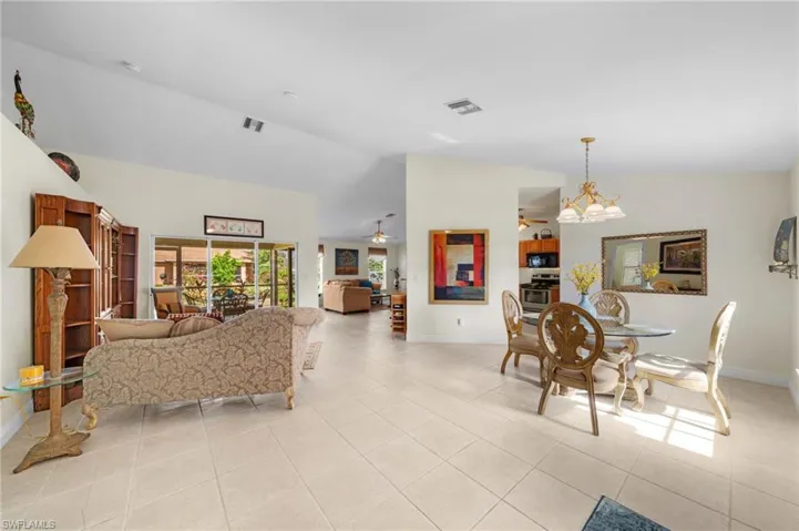 Living room featuring baseboards, light tile patterned flooring, a ceiling fan, high vaulted ceiling, and a chandelier