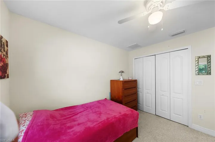 Carpeted bedroom with a closet, baseboards, and a ceiling fan