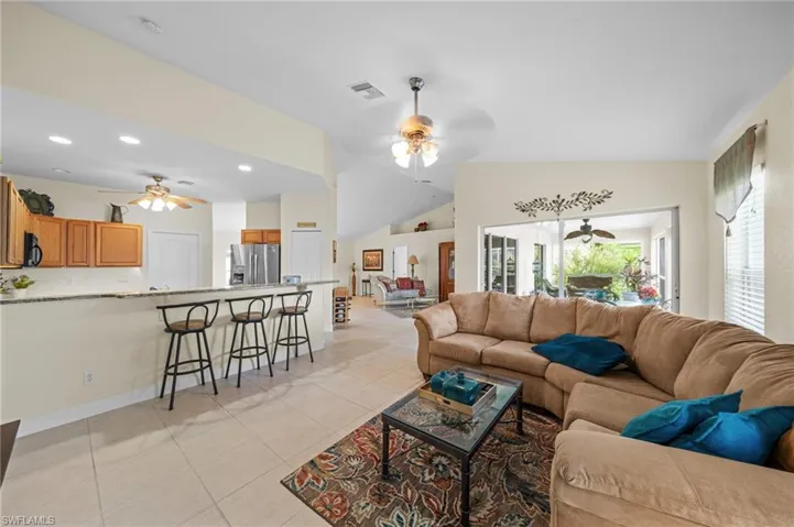 Living room with ceiling fan, light tile patterned floors, lofted ceiling, and recessed lighting