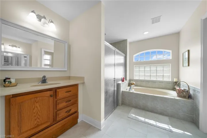 Full bath with healthy amount of natural light, a bath, vanity, and a shower stall