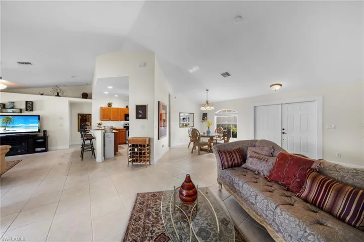 Living room with light tile patterned floors, a chandelier, baseboards, and high vaulted ceiling