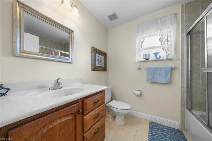 Full bath with vanity, toilet, baseboards, tile patterned flooring, and shower / bath combination with glass door
