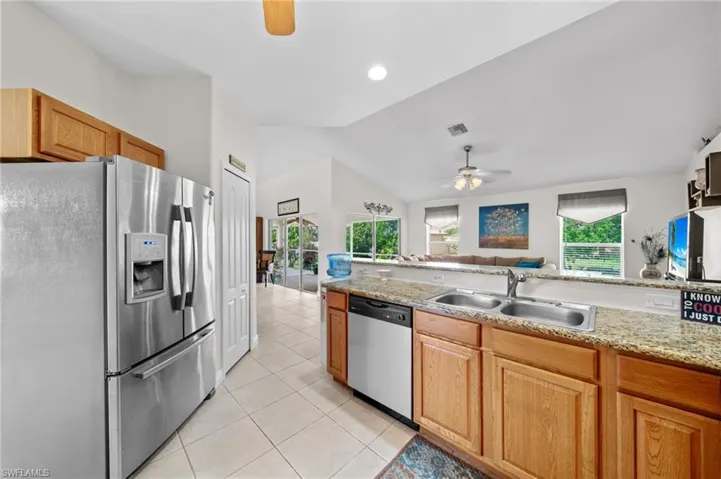 Kitchen with stainless steel appliances, a sink, ceiling fan, light tile patterned floors, and lofted ceiling