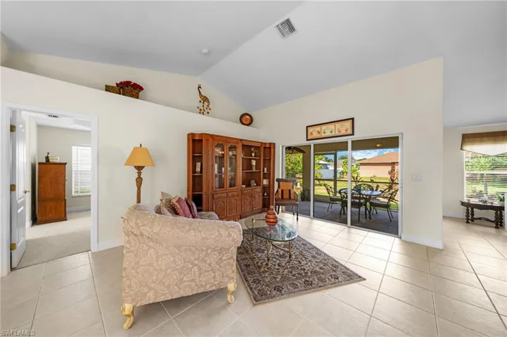 Living area with lofted ceiling, light tile patterned floors, and baseboards
