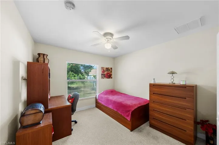 Carpeted bedroom with baseboards, an office area, and ceiling fan