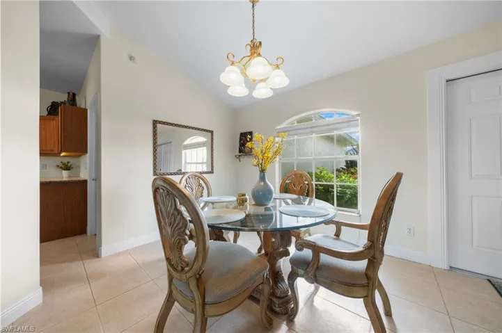 Dining area featuring a chandelier, light tile patterned flooring, vaulted ceiling, and baseboards