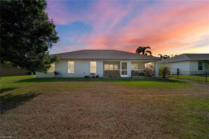 Back of house at dusk featuring stucco siding and a sunroom