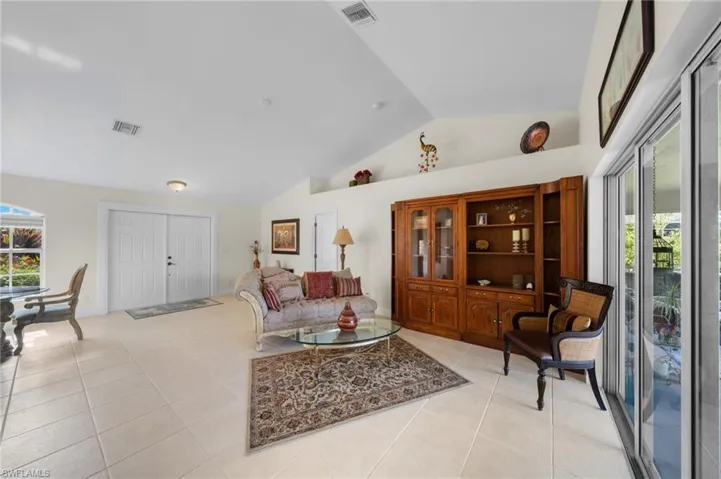 Living area with light tile patterned flooring and high vaulted ceiling