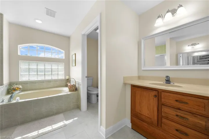 Full bath with vanity, a bath, toilet, and tile patterned floors