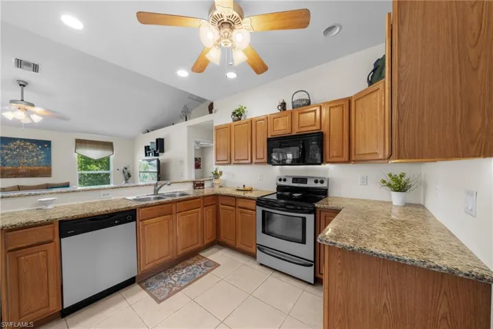 Kitchen featuring stainless steel appliances, a ceiling fan, vaulted ceiling, a peninsula, and light tile patterned flooring