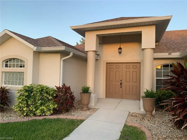 View of exterior entry with stucco siding and a shingled roof