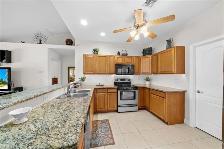Kitchen featuring electric stove, black microwave, a sink, ceiling fan, and light tile patterned floors