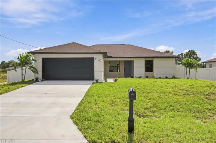 Single-story residence featuring a smooth stucco facade, a dark-toned hipped roof, a two-car garage, and a full-length concrete driveway