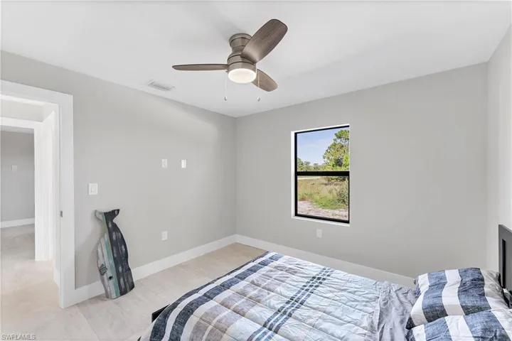 Neutral interior featuring light-toned walls, wood-finish flooring, a ceiling fan with integrated lighting, and a single-pane window with a dark frame