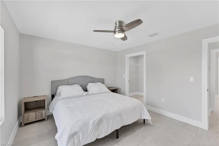 Neutral interior palette with light-toned tile flooring, brushed nickel ceiling fan with integrated lighting, and walk-in closet featuring built-in wire shelving