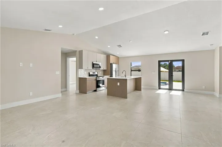 Open-concept interior featuring large-format tile flooring, recessed lighting, and vaulted ceilings