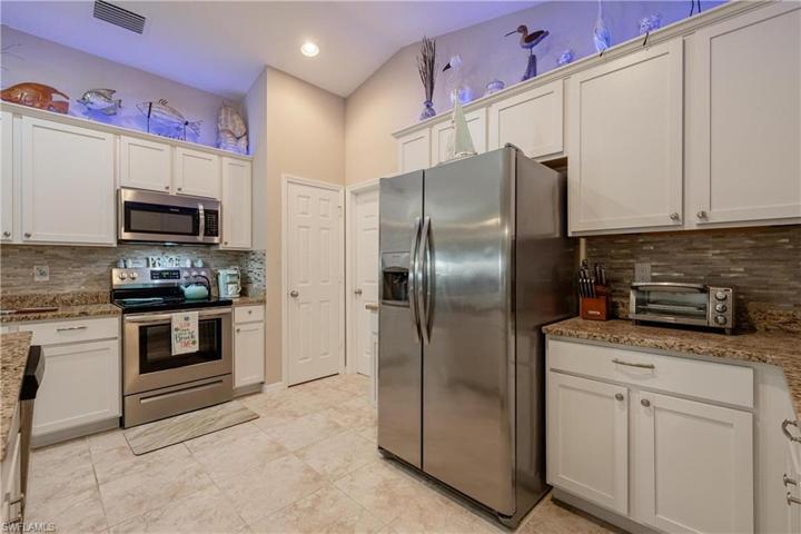 Custom Kitchen with upgrades that include granite countertops, modern light backsplash, soft close white cabinetry, crown molding, stainless steel appliances, additional lighting, island, and pantry.