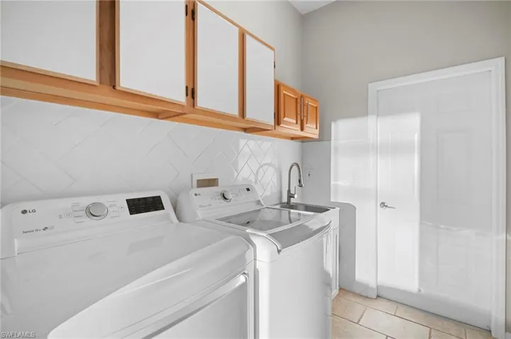 Laundry area featuring cabinet space, washer and dryer, and light tile patterned floors