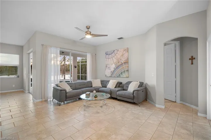 Living area featuring ceiling fan, arched walkways, and light tile patterned floors