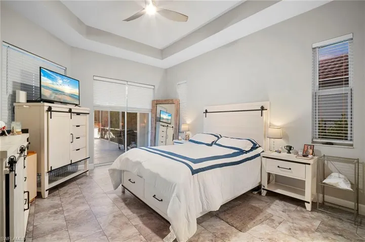 Bedroom with a tray ceiling, a ceiling fan, and access to outside