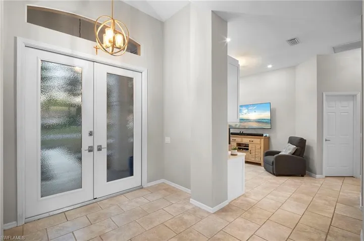 Doorway with french doors, suspended lighting, and tile patterned flooring