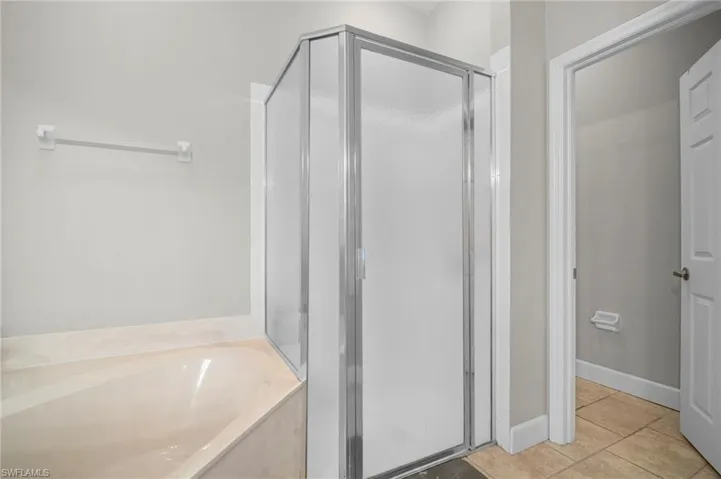 Bathroom featuring a shower stall, a garden tub, and light tile patterned flooring