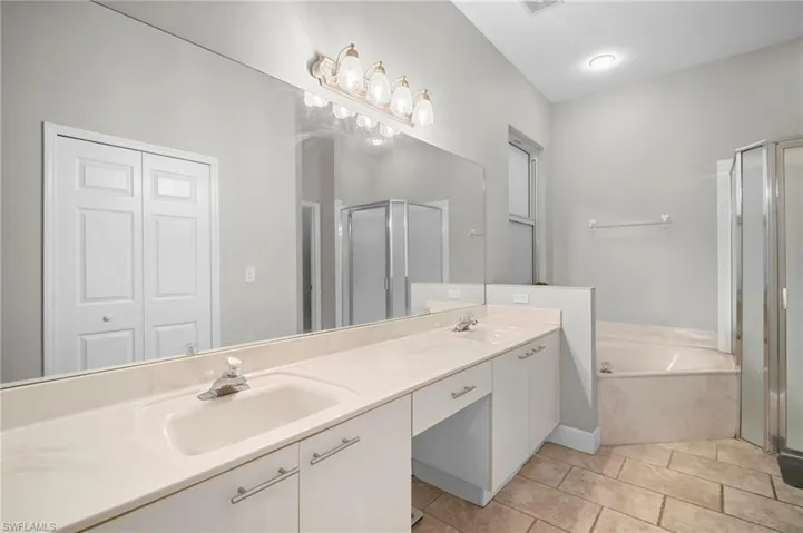 Bathroom with double vanity, a stall shower, a garden tub, a closet, and light tile patterned flooring