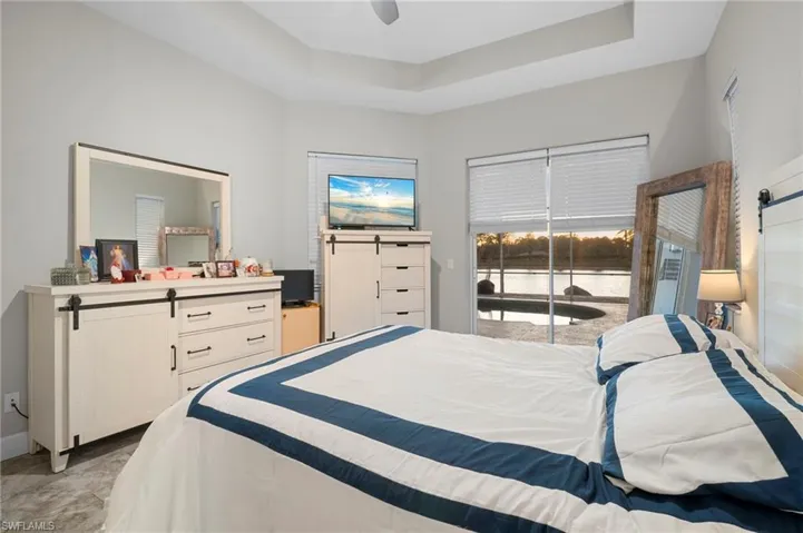 Bedroom featuring a tray ceiling, access to exterior, ceiling fan, and light colored carpet