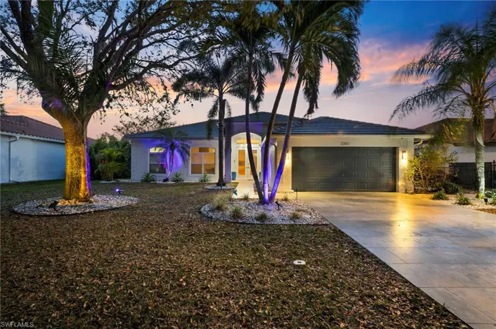 View of front of house featuring a garage, concrete driveway, and a lawn