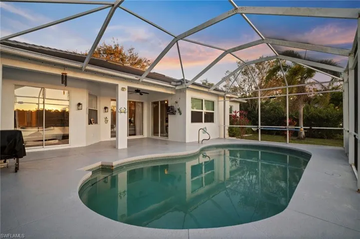 Pool at dusk with a sunroom, an outdoor pool, and glass enclosure